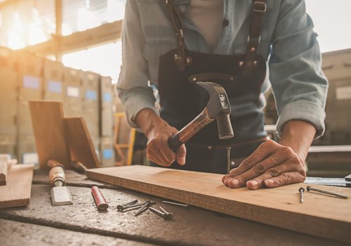 Carpenter working with equipment on wooden table in carpentry sh