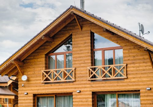 Modern wooden house with big windows and balcony. Concept of building of family houses, pensions or cottages in the countryside. Building of houses under the key
